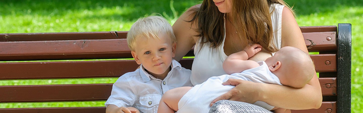 Mom breastfeeding child on a park bench