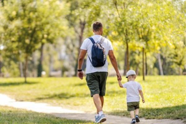 Man and child holding hands and walking in the park