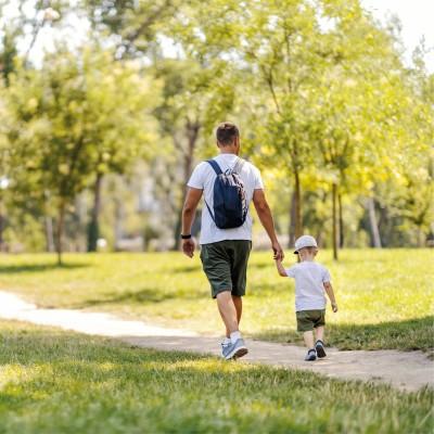 Man and child holding hands and walking in the park