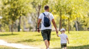 Man and child holding hands and walking in the park